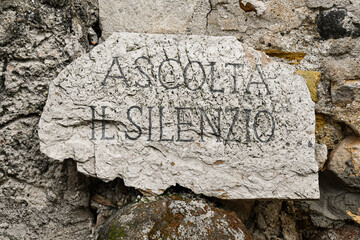 Close-up of a stone wall with an engraving that says: "Listen to the silence", Italy