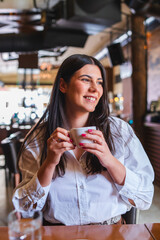 A one young girl or woman is drinking coffee in cafe or restaurant and enjoying her time
