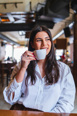 A one young girl or woman is drinking coffee in cafe or restaurant and enjoying her time
