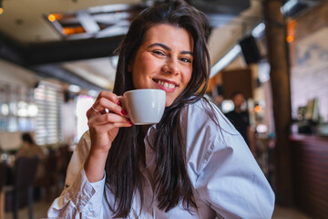 A one young girl or woman is drinking coffee in cafe or restaurant and enjoying her time
