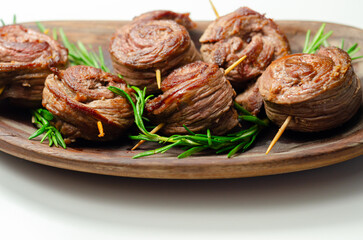 A plate of pieces of meat in the shape of roses with green herbs on top - 776206672