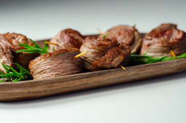 A plate of pieces of meat in the shape of roses with green herbs on top - 776207013
