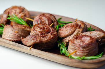 A plate of pieces of meat in the shape of roses with green herbs on top - 776207019