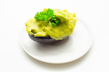 A green avocado with parsley on top sits on a white plate - 776207482