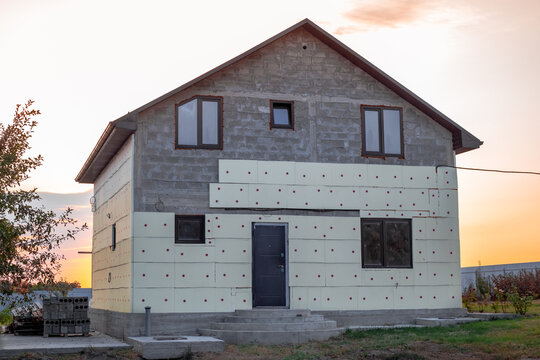 Construction of a two-story house. The stage of exterior finishing and insulation of the walls of a block house using penoplex
