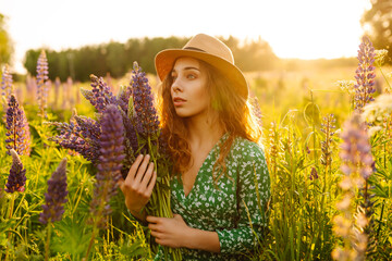 Portrait of young woman holding bouquet of lavender flowers walking in summer meadow. Nature,...