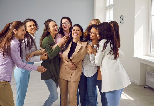 Group of happy diverse female colleagues laughing or hugging together. Group portrait of beautiful overjoyed multiethnic young women in smart casual wear posing together in office