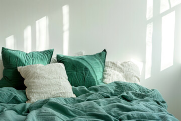 Emerald green bedding on bed with pillows against white wall with copy space in bedroom interior.