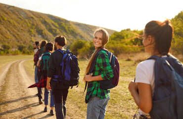Portrait features a confident woman hiker surrounded by a group of friends. Together, team exploring new horizons and creating unforgettable memories during vacation hike travel.