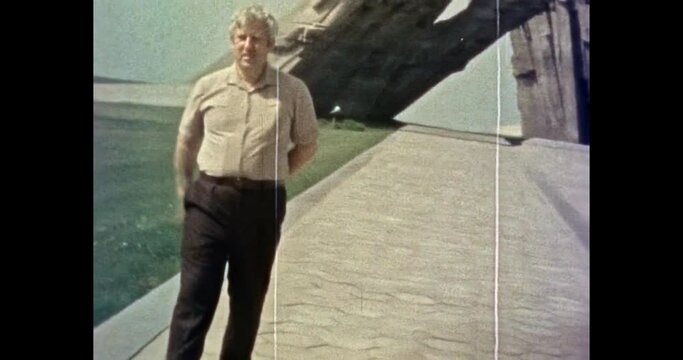 Man tourist next to monument to fascism victims. Kaunas, Lithuania 1980s. Man background of art object, travel memorial on summer street. Vintage color film archive. Retro, overscan archival video