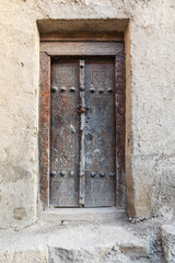Fototapeta na wymiar An old wooden door on an adobe building in Bukhara.