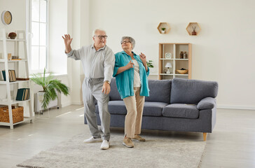 Happy senior family couple wife and husband dancing in the living room at home. Two smiling retired man and woman having fun, enjoying happy life moments and time together on retirement. - 776225672