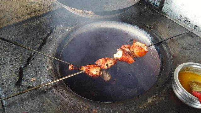 Cooking tandoori chicken in fire flame