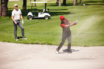 Men, stroke and golf ball in bunker on summer day for sports, health or exercise outdoor in...