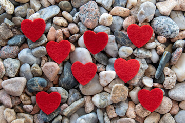 Much red fabric hearts on the river pebble stones.