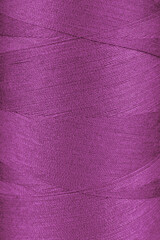 Texture of pink color threads in spool close up, macro. Sewing threads bobbin abstract background, wallpaper, backdrop.