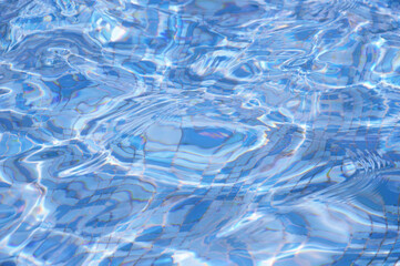Abstract background of blue water glare on the surface in a pool, fountain on a sunny day.