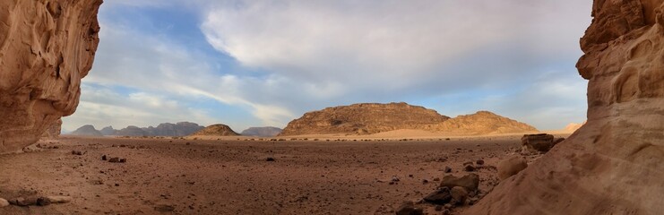 Panoramic view of Wadi Rum desert in Jordan with clouds moving over flat sand landscape with...