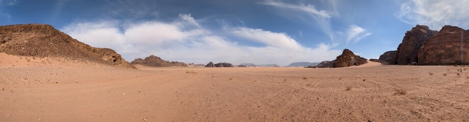 Fototapeta na wymiar Panoramic view of Wadi Rum desert in Jordan with clouds moving over flat sand landscape with mountains and rocks formations.Discover beauty of the earth. National park outdoors landscape.UNESCO