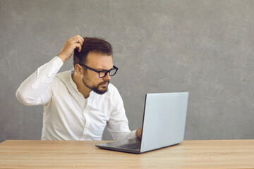 Portrait of confused man looking at computer screen. Puzzled employee, office worker, student or hipster feeling dumb and stupid trying to understand hard complicated stuff or fix PC software problem - 776246257