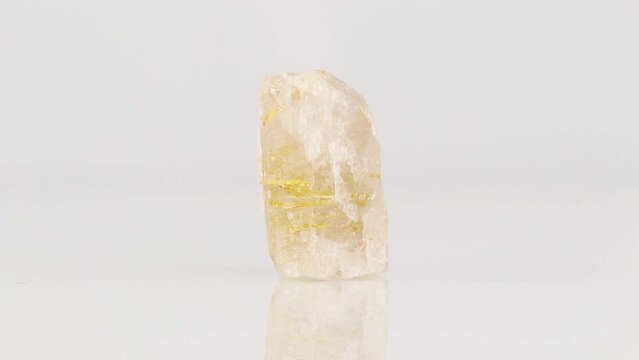 Polished mineral stone Rutile in quartz in zoisite rotates in a circle on a white background close-up