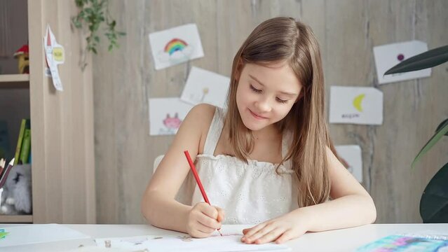 Young girl concentrating on drawing at the desk at home or school class room