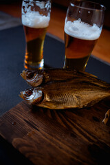 Foam beer in a mug, dried fish stockfish dark background. Beer brewery concept