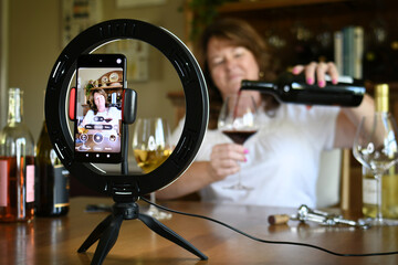 Female leading virtual wine tasting online video social media or live stream with light ring & phone