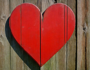Bright red heart as a symbol of love and friendship on the old wooden wall