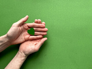 Male hands holding a green paper heart on a green background, Earth Day, April 22.
