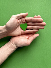 Male hands holding a green paper heart on a green background, Earth Day, April 22.