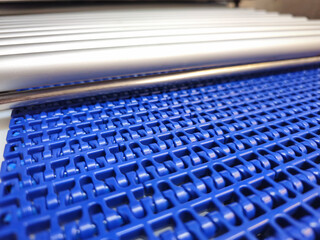 A close-up of a blue polyurethane belt in modular industrial conveyor system connected with roller...