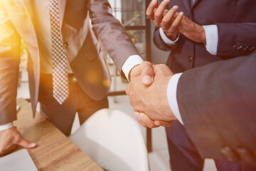 Two young businessmen are shaking hands with each other.