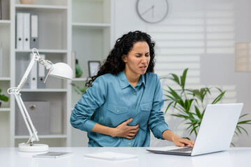 Professional woman experiencing discomfort while seated at a workstation, indicating possible...