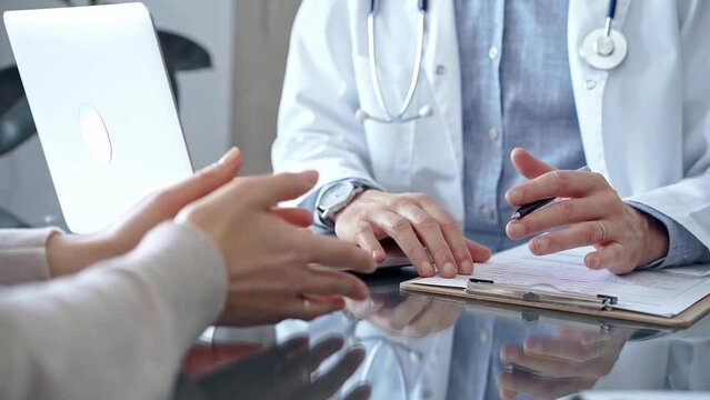 Doctor consulting patient using a clipboard for making notes. Medical office in clinic. Medicine concept