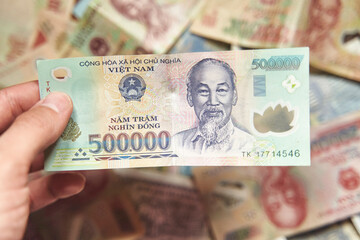 Male hand holds a fan of Vietnames Dong banknote, the currency of Vietnam. Close up Polymer Money of Vietnam. 500000 Dong or VND in male hand. In front a portrait of Ho Chi Minh. Plastic banknotes