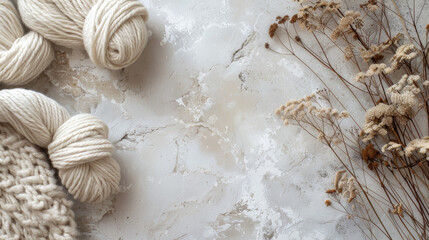  Wool yarn balls and dry flowers on grey textured background.