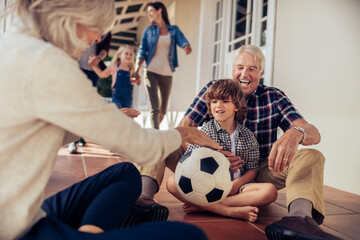 Grandparents and grandchildren having fun with a soccer ball on house porch