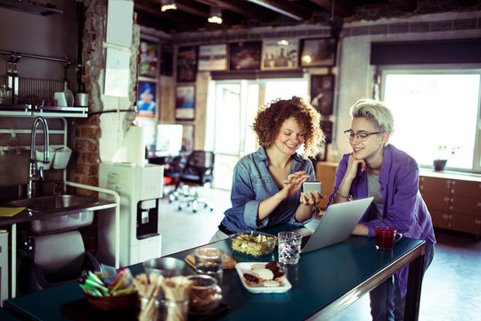 Young women using a smart phone while having a lunch break in a startup company office
