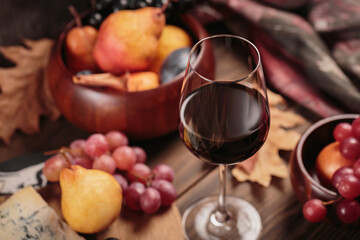 Glass of red wine served with blue cheese on dark wooden background. Autumn picnic with wine and...