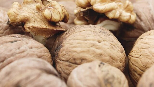 Walnuts heap close-up with a focus on a cracked nutshell