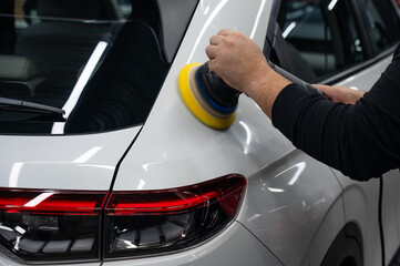 Fototapeta premium Process of polishing white car body surface using orbital polishing machine. 
