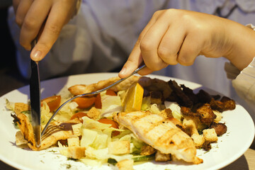 Person Cutting Into Plate of Food With Knife and Fork
