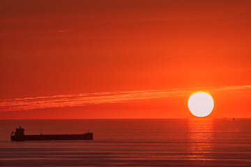 Sunset from Punta Galea, Getxo over the Cantabrian Sea with a round sun touching the horizon, a...