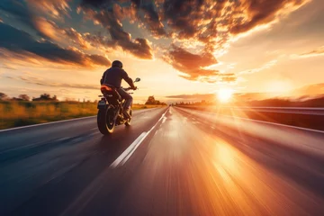 Selbstklebende Fototapeten A motorcyclist rides on a highway towards the sunset, with the dynamic landscape blurring past © Anna
