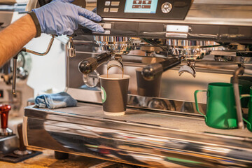 Barista preparing coffee in takeaway cups in coffee shop. Professional Coffee Brewing in Coffee...