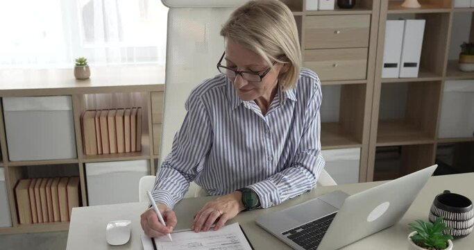 Mature woman businesswoman sign document contract at office at work