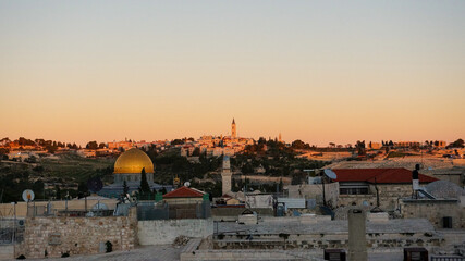 Obraz premium The golden hour casts a warm glow over Jerusalem's skyline, with the iconic Dome of the Rock shining against the ancient city's silhouette