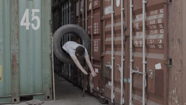 Stunt man diving through tire between shipping containers - epic slow motion