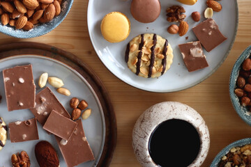 Cup of tea or coffee, cookies, macaroons, chocolate, various nuts and cocoa powder on wooden table. Top view.